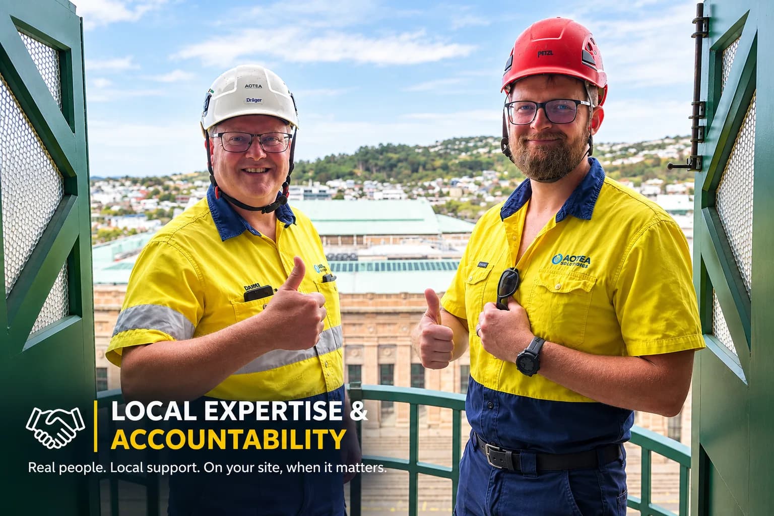 Two Aotea Solutions team members in hi-vis and hard hats giving a thumbs up on site in Wellington